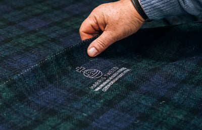 A person holding a piece of Harris Tweed cloth.