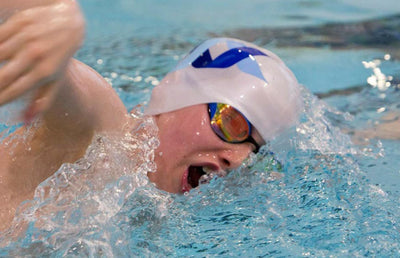 A person swimming with a North Ayrshire swimming logo swimming cap.