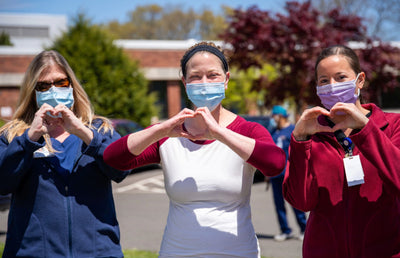 Three doctors creating heart shapes with their hands.