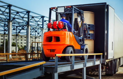 A worker from Logos Logistics loading machinery into a truck.