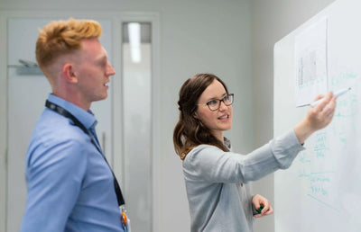 Two people in front of a whiteboard.
