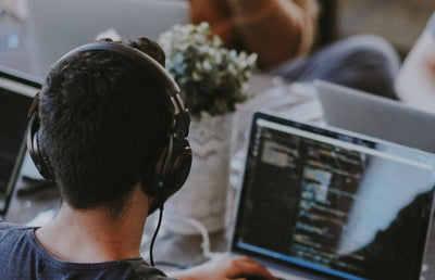 Someone wearing headphones and using a laptop.