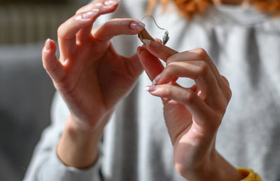 Someone adjusting the volume on a hearing aid.