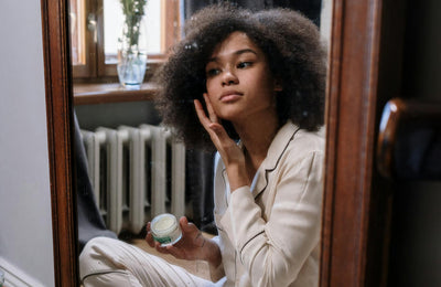 A woman applying skin cream.