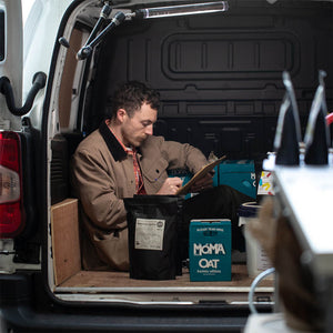 A Machina Coffee worker packing some coffee.