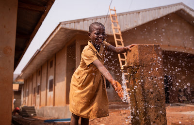 A kid pouring water from a water tap.