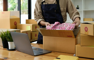 Someone packing a shirt into a box for shipping