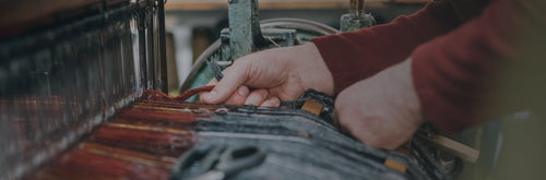 A Harris Tweed worker threading wool into the machine.